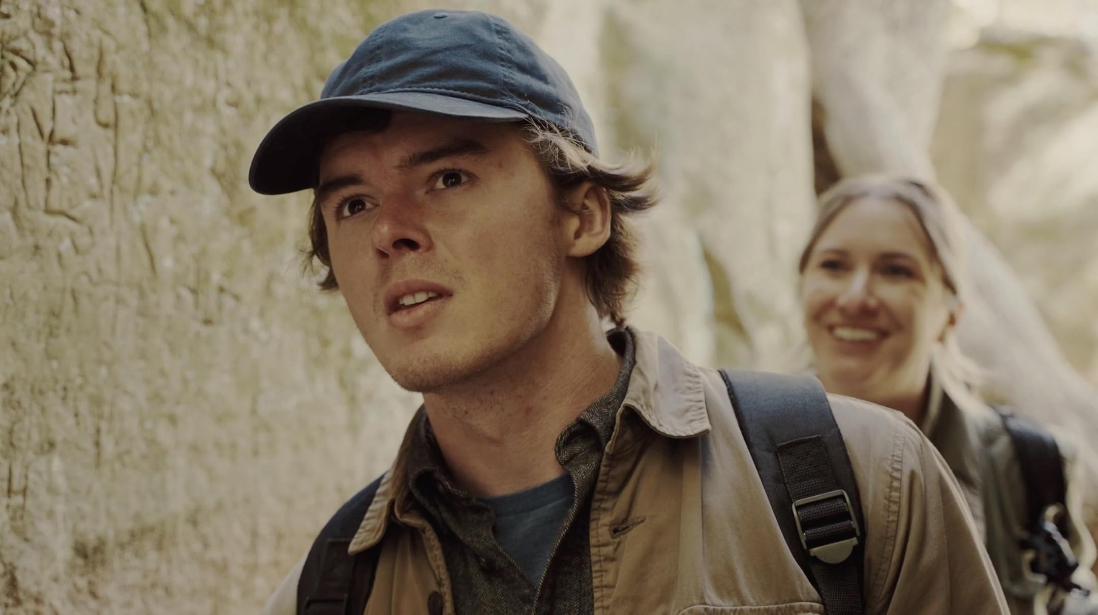 Dramatic poster of an isolated lighthouse on a rocky cliff being battered by massive storm waves under dark stormy skies with a single beam of light cutting through the darkness